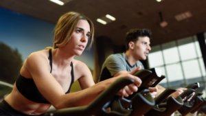 The purpose of this image is to highlight a couple working out together, likely in a gym setting, as a fun and active bonding activity. The image shows both individuals focused and engaged, suggesting that exercising together can be a shared experience that strengthens connections, whether indoors or for future outdoor dates involving fitness.