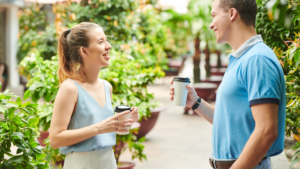 The purpose of an image showing a couple holding a cup of coffee while standing in front of each other and smiling on a sunny day could be to evoke feelings of warmth, intimacy, and happiness. It could symbolize a moment of connection and joy between two people, perhaps suggesting a romantic relationship or a close bond between friends or family members. The sunny day adds a sense of positivity and brightness to the scene, enhancing the overall mood of the image.