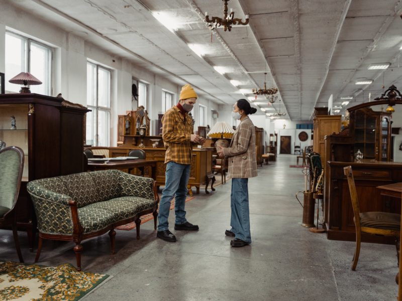 The purpose of the image is to depict a scene where a man is engaging in conversation with a woman inside a furniture shop. The man appears to be either initiating a conversation or asking a question, while the woman listens attentively or responds. The alt text "Top 3 conversation with a girl" suggests that the conversation may be centered around topics that are commonly discussed when interacting with a woman, such as shared interests, opinions on furniture choices, or general small talk.
