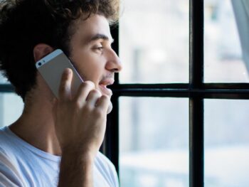 This image shows a young man on the phone, possibly engaged in a conversation. It highlights a common scenario where scammers might try to gain trust over a call. To know if someone is a scammer, be wary of unexpected phone calls where the person pressures you into quick decisions or asks for personal details like bank information.