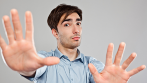 The photo depicts a moment of hesitation or boundary-setting in a relationship. The man's raised hands and serious expression symbolize stepping back or creating distance, illustrating "When should you stop dating someone?"—a point often reached when facing discomfort, red flags, or potential issues.