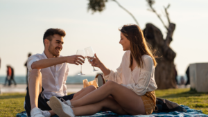 The image shows a man enjoying a relaxed picnic date, symbolizing the idea of "Staying Present to Overcome Shyness" by engaging in a mindful and enjoyable moment together.