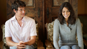 This image seems to be illustrating a scenario of dating as a shy guy. It features a young man and woman sitting next to each other, with the man appearing a bit nervous or shy, while the woman is smiling warmly. The purpose of this image is likely to provide a visual representation of tips or advice on "How To Date As A Shy Guy." It captures the essence of initial awkwardness and the potential for positive interaction despite shyness.