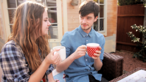 This image captures a casual and friendly moment between a man and a woman, sharing a cup of coffee or tea, possibly hinting at the comfort and ease in their relationship. It is ideal for illustrating the concept of when to ask that friend out.