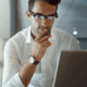 Man thinking deeply while looking at his laptop, symbolizing reflection and personal research.
