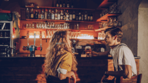 A man and woman having a calm conversation over drinks at a cozy bar, capturing a moment of connection while dating as a quiet guy.