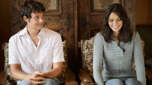 A shy man and a smiling woman sitting side by side, capturing a relatable moment for the topic do women like shy guys.