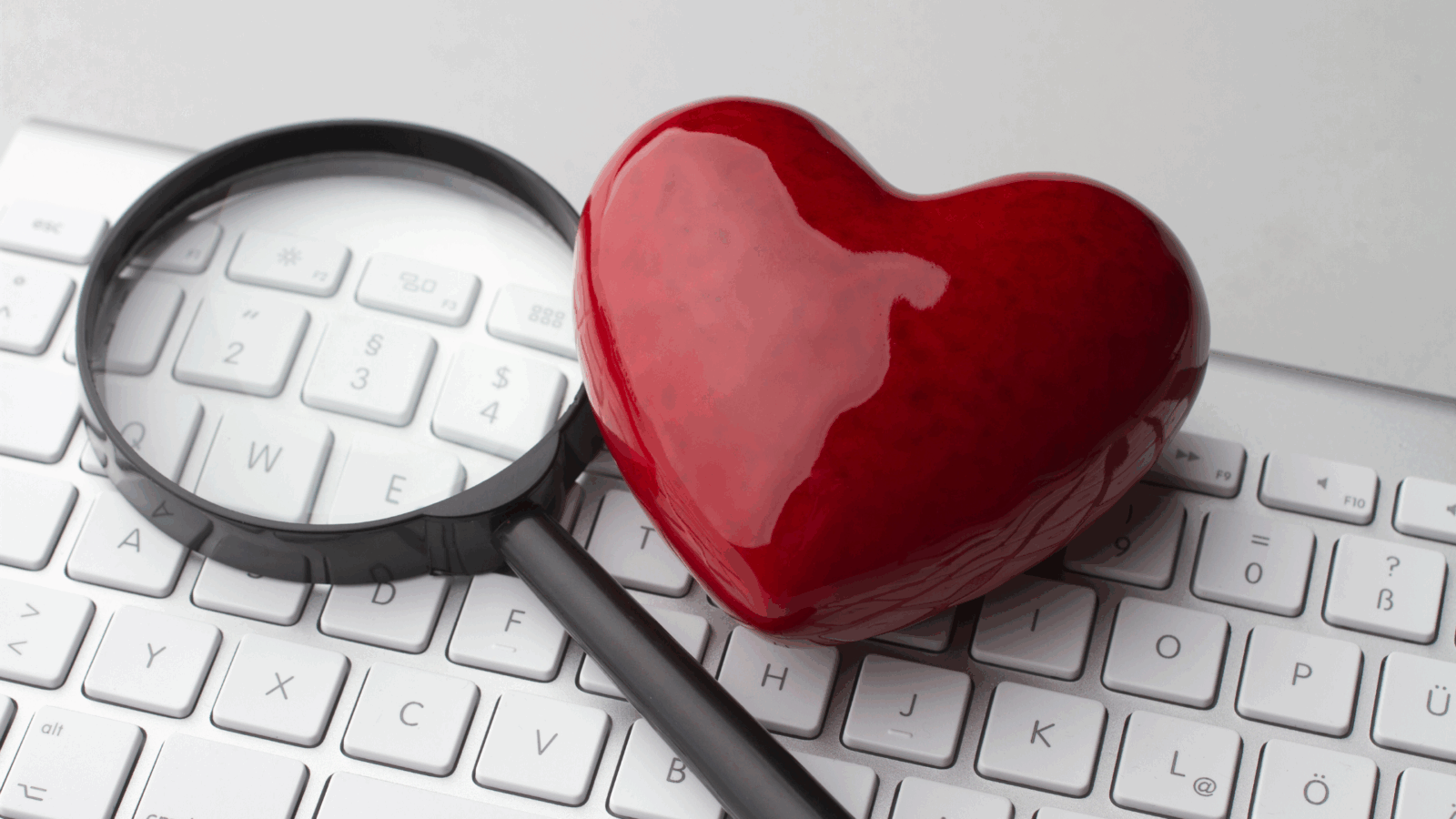 A red heart and magnifying glass on a keyboard, symbolizing the best places to meet women as an introvert through meaningful connections.