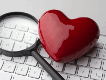 A red heart and magnifying glass on a keyboard, symbolizing the best places to meet women as an introvert through meaningful connections.