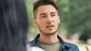 A man engaged in a conversation, possibly explaining his thoughts or feelings.