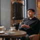 AI dating advice — man talking at coffee shop table with phone and coffee nearby