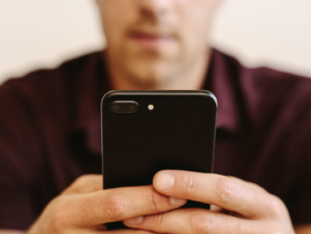 Close-up of a man holding a phone editing his dating profile