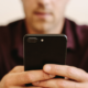 Close-up of a man holding a phone editing his dating profile