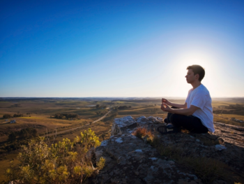 Man healing his heart chakra after a breakup, sitting alone in nature